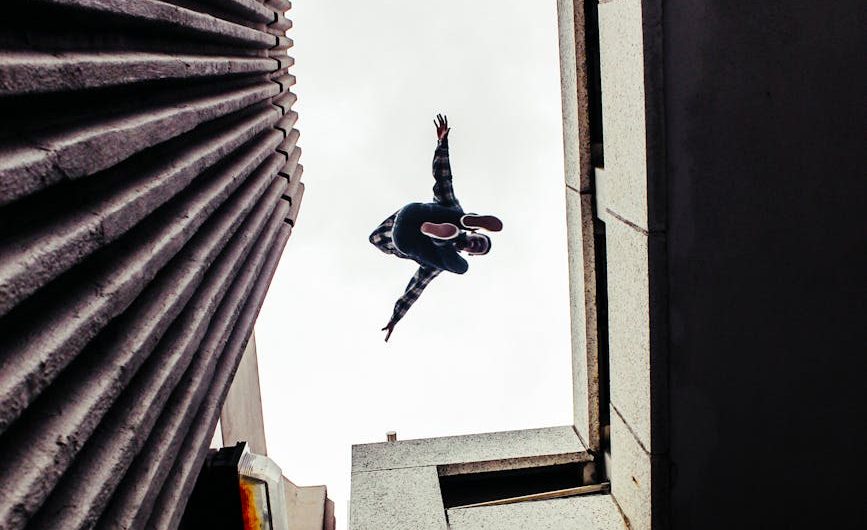 a person jumping off from gray concrete building
